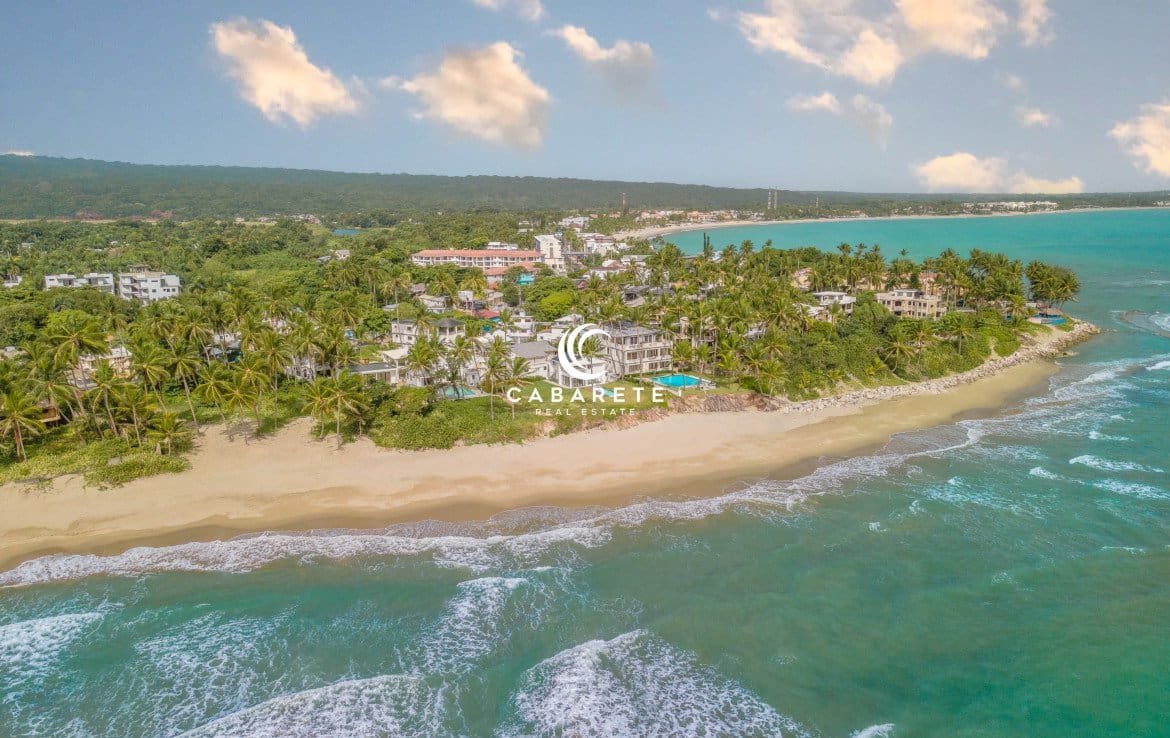 Vue aérienne depuis l'océan d'une maison de 4 chambres à coucher en bord de mer à vendre à Cabarete, Puerto Plata, mettant en valeur la plage et le cadre de la maison.