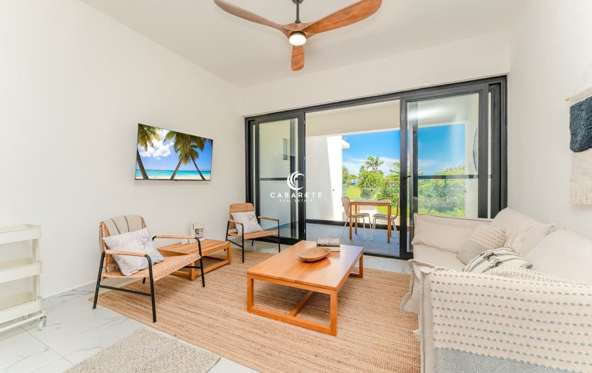 Modern living room with comfortable seating, a ceiling fan, and sliding glass doors leading to a balcony.