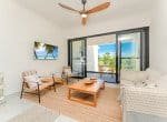 Modern living room with comfortable seating, a ceiling fan, and sliding glass doors leading to a balcony.