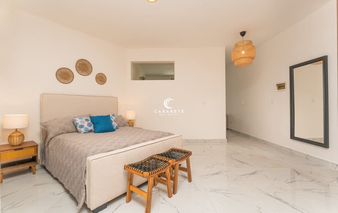 Beautifully decorated bedroom features a king-size bed, a large mirror, and stylish wall decor.