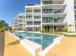 Modern apartment complex with a swimming pool and surrounding amenities.