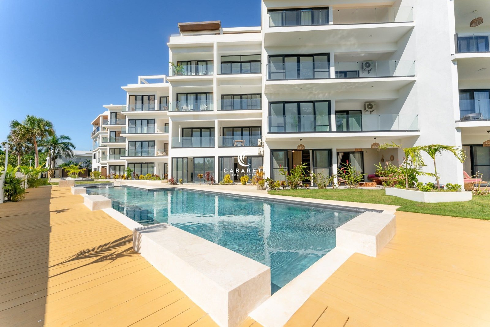Moderno complejo de apartamentos con piscina y servicios circundantes.