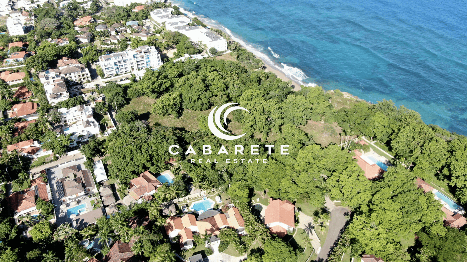 Bird’s-eye view of large undeveloped beachfront plot bordered by clear waters and green vegetation