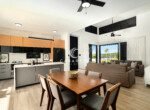 open concept kitchen dining living room with island and greenery view