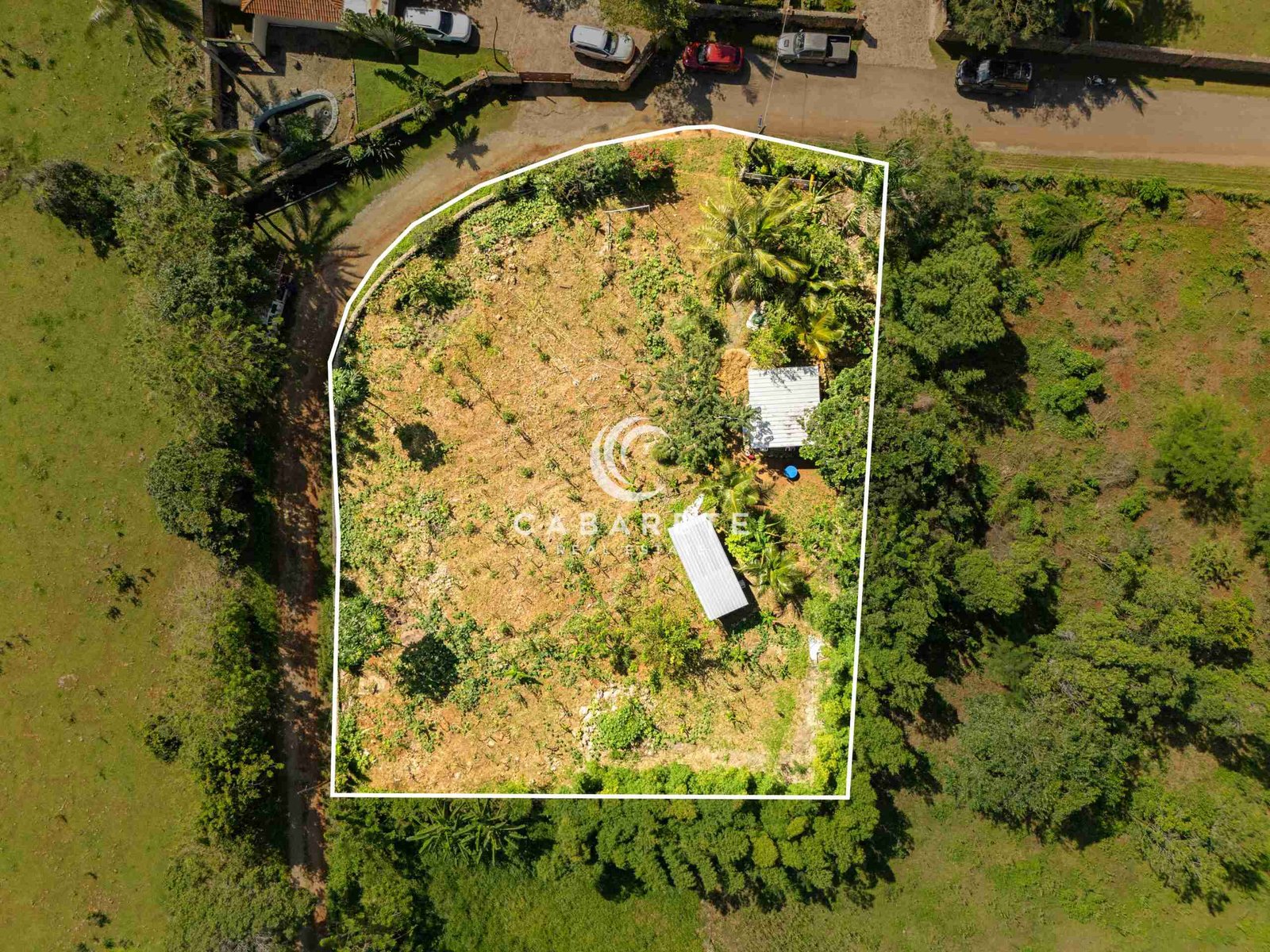 Aerial view showing cultivated garden land with metal roof sheds and ocean dream apartment nearby